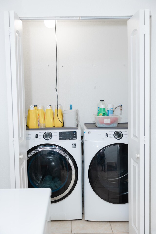 clothes washing area with independent washer and dryer and light tile patterned floors