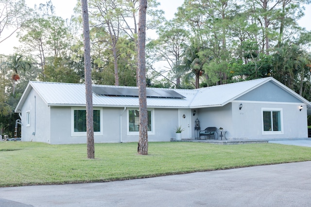 ranch-style house featuring solar panels and a front yard