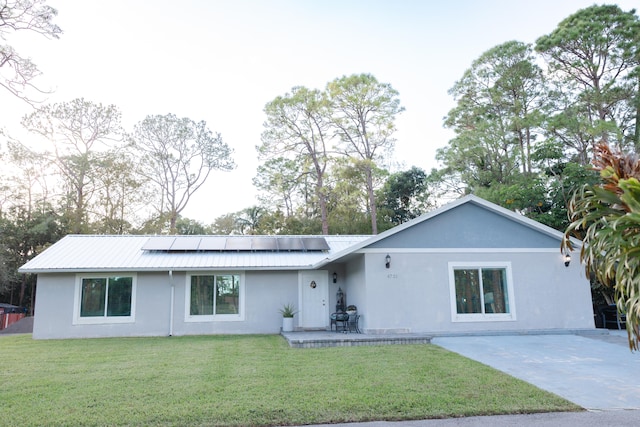 ranch-style house featuring a patio, solar panels, and a front lawn