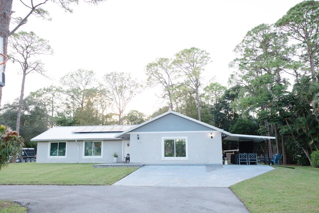 ranch-style house with a carport, a front lawn, and solar panels