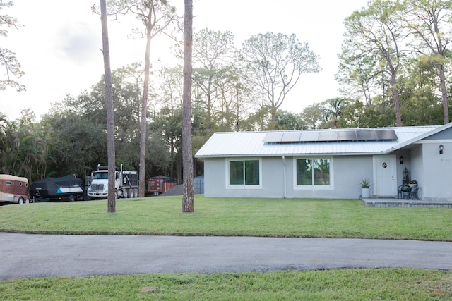 view of property exterior with solar panels and a lawn