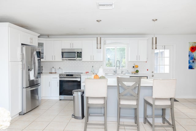 kitchen with sink, pendant lighting, white cabinetry, and stainless steel appliances