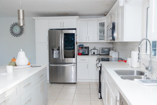 kitchen with tasteful backsplash, appliances with stainless steel finishes, sink, white cabinets, and light tile patterned floors