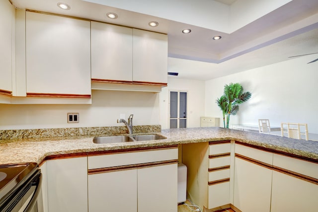 kitchen with kitchen peninsula, white cabinetry, sink, and range with electric stovetop