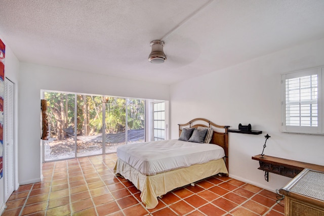 tiled bedroom with ceiling fan, a textured ceiling, and access to exterior