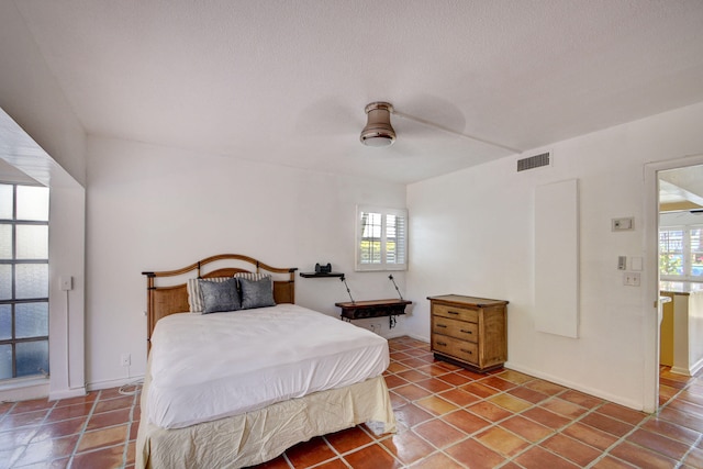 bedroom featuring multiple windows, a textured ceiling, tile patterned floors, and ceiling fan