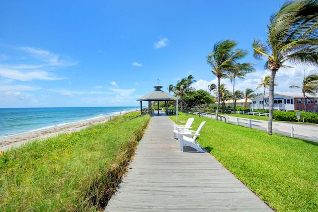 view of property's community with a gazebo, a view of the beach, a water view, and a yard