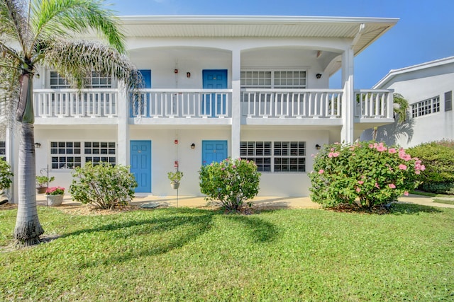 rear view of house featuring a balcony and a lawn