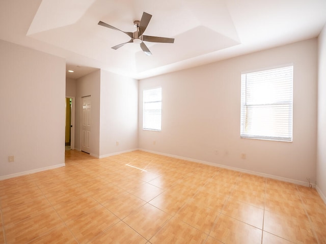 unfurnished room with ceiling fan, a tray ceiling, and light tile patterned floors