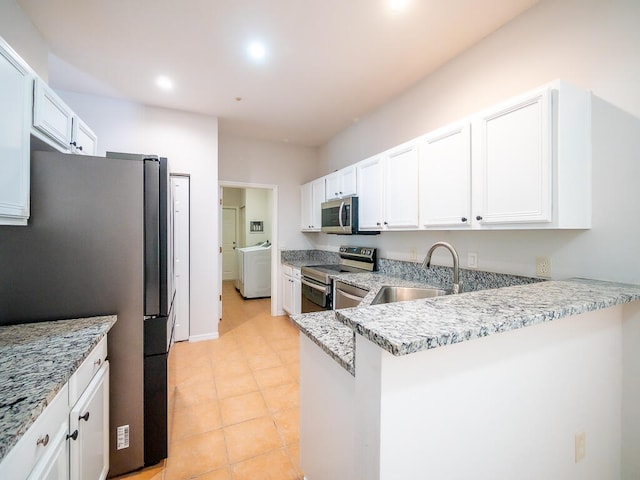 kitchen featuring kitchen peninsula, white cabinets, washer / clothes dryer, appliances with stainless steel finishes, and sink