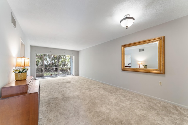 spare room with a textured ceiling and carpet flooring