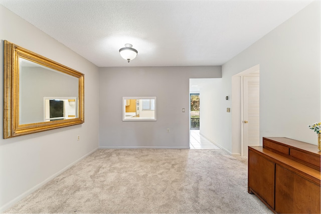 spare room with a textured ceiling and light colored carpet