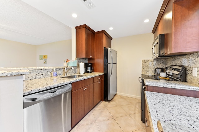 kitchen featuring backsplash, sink, light stone countertops, light tile patterned flooring, and appliances with stainless steel finishes