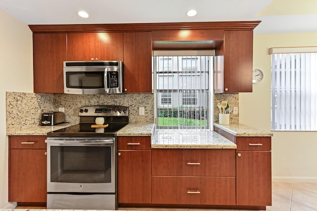 kitchen with stainless steel appliances, light stone countertops, light tile patterned flooring, and tasteful backsplash