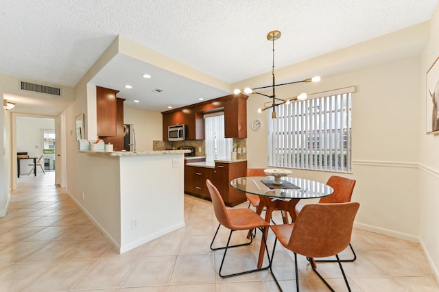 dining room with a textured ceiling, light tile patterned floors, and an inviting chandelier