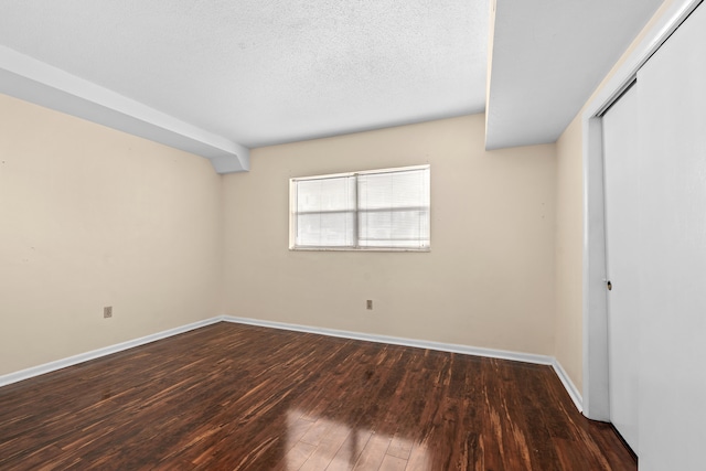 spare room featuring dark hardwood / wood-style floors and a textured ceiling