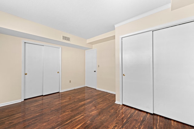 unfurnished bedroom with dark hardwood / wood-style floors and two closets