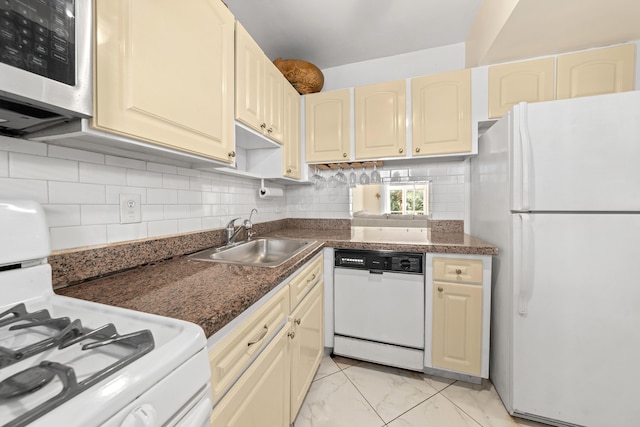 kitchen featuring decorative backsplash, cream cabinets, sink, and white appliances