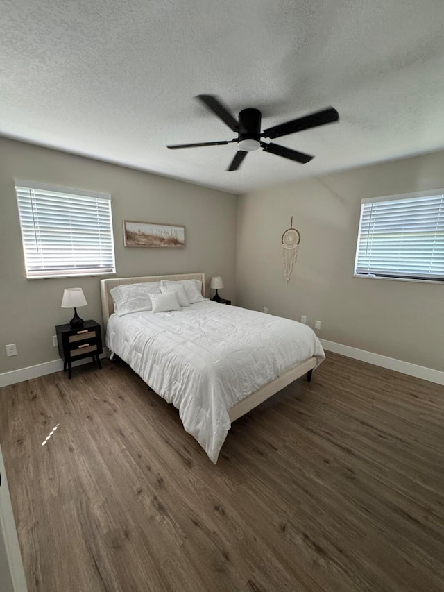 unfurnished bedroom featuring dark hardwood / wood-style flooring, multiple windows, a textured ceiling, and ceiling fan