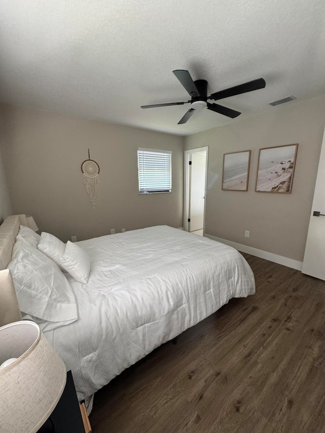 bedroom with a textured ceiling, dark hardwood / wood-style floors, and ceiling fan