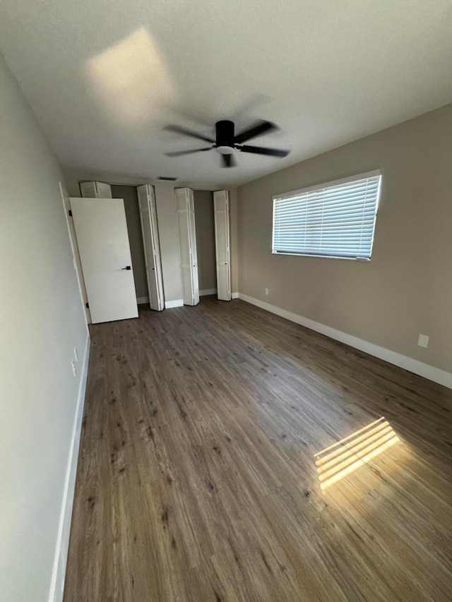 unfurnished bedroom with ceiling fan, a textured ceiling, and dark hardwood / wood-style floors