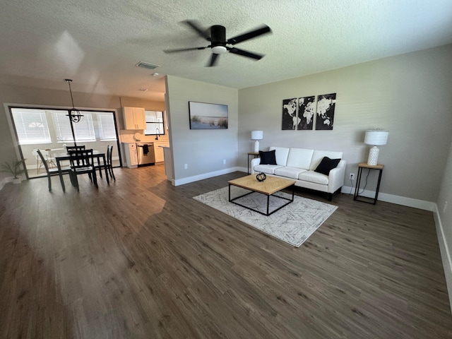 living room with dark hardwood / wood-style floors, a textured ceiling, and ceiling fan