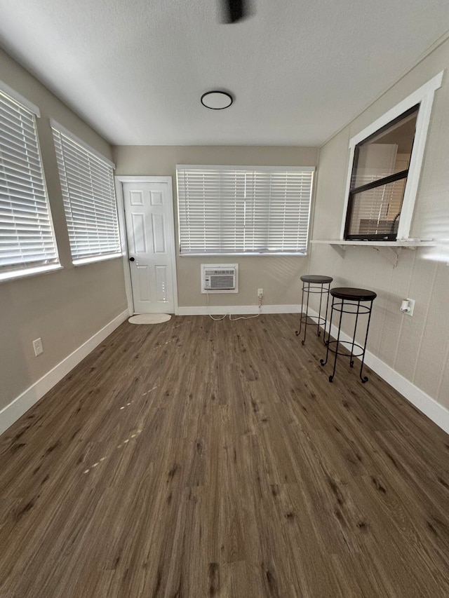 unfurnished living room with a wall mounted AC, a textured ceiling, and dark hardwood / wood-style flooring