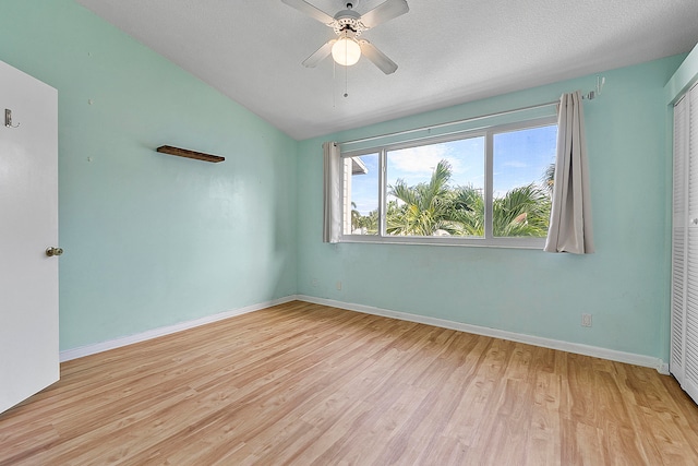 spare room featuring vaulted ceiling, light hardwood / wood-style flooring, a textured ceiling, and ceiling fan