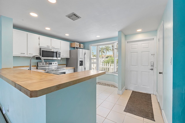 kitchen featuring kitchen peninsula, white cabinetry, light tile patterned flooring, sink, and stainless steel appliances