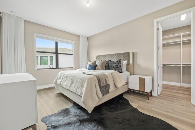 bedroom featuring a walk in closet, light wood-type flooring, and a closet