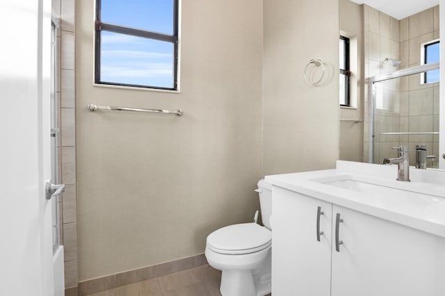 bathroom featuring vanity, toilet, and a shower with door