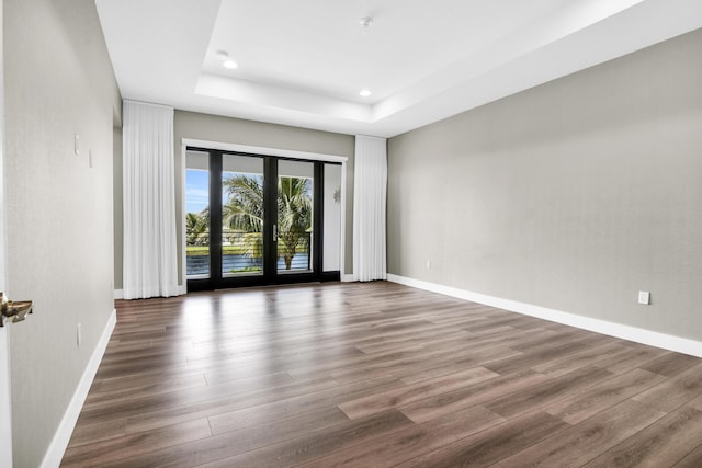 unfurnished room featuring a raised ceiling, dark wood-type flooring, and french doors