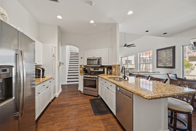 kitchen featuring sink, a kitchen bar, white cabinetry, stainless steel appliances, and dark wood-type flooring