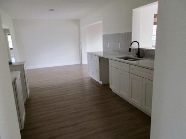 kitchen featuring dark hardwood / wood-style flooring, sink, backsplash, and white cabinets