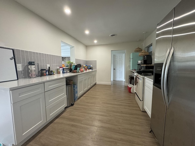 kitchen with white cabinets, decorative backsplash, stainless steel fridge, and white range with electric cooktop