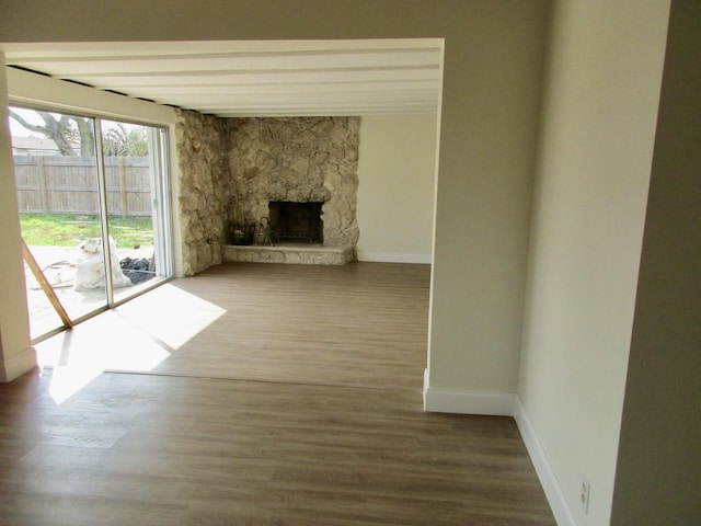 unfurnished living room featuring hardwood / wood-style floors and a stone fireplace