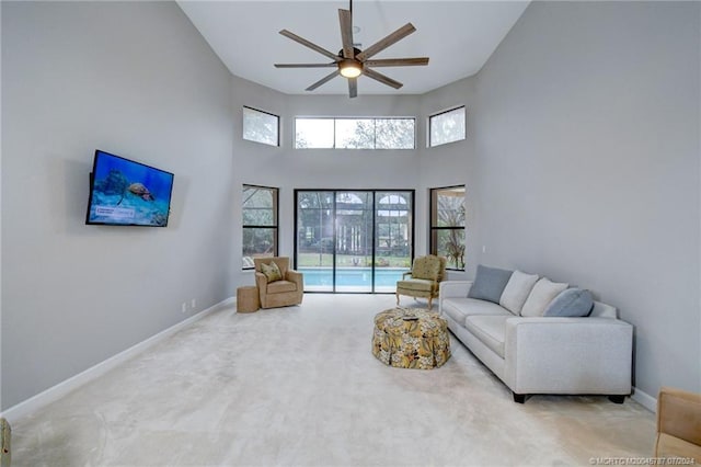 carpeted living room with ceiling fan and a high ceiling