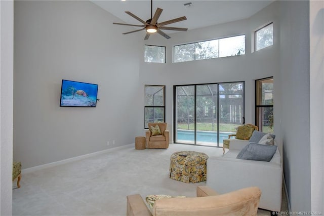 carpeted living room with a high ceiling and ceiling fan