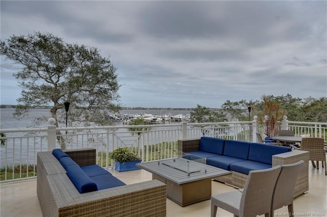 view of patio with an outdoor living space with a fire pit, a water view, and a balcony