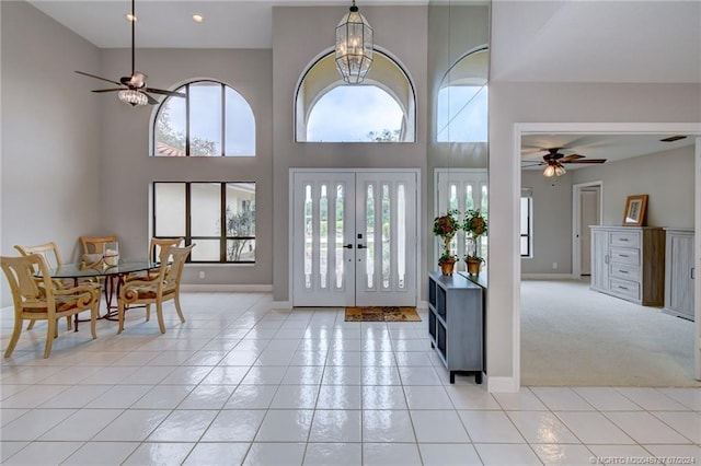 entryway with a towering ceiling, plenty of natural light, light carpet, and ceiling fan