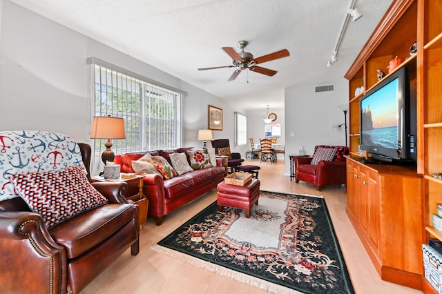 living room featuring ceiling fan, a textured ceiling, track lighting, and light wood-type flooring