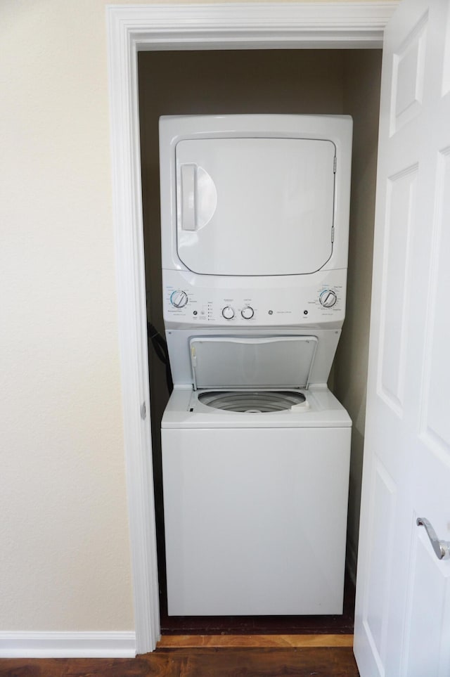 laundry room featuring stacked washer / dryer and dark hardwood / wood-style floors