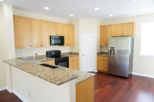 kitchen with kitchen peninsula, black appliances, sink, light stone counters, and dark hardwood / wood-style flooring