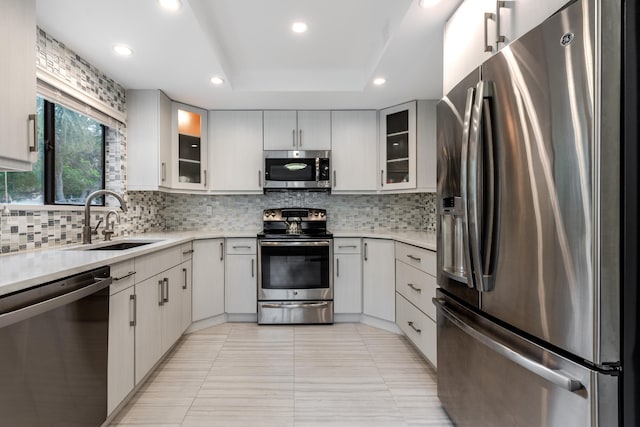 kitchen featuring light tile patterned floors, stainless steel appliances, sink, a raised ceiling, and tasteful backsplash