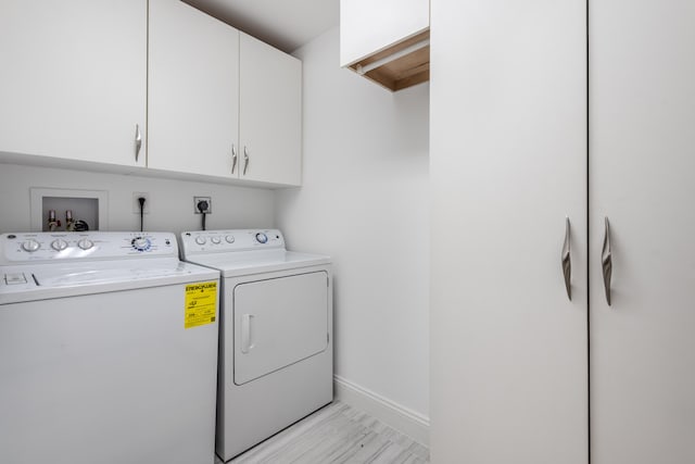 laundry room featuring cabinets, light wood-type flooring, and washing machine and clothes dryer