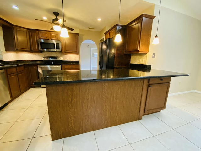 kitchen featuring ceiling fan, light tile patterned floors, stainless steel appliances, and hanging light fixtures