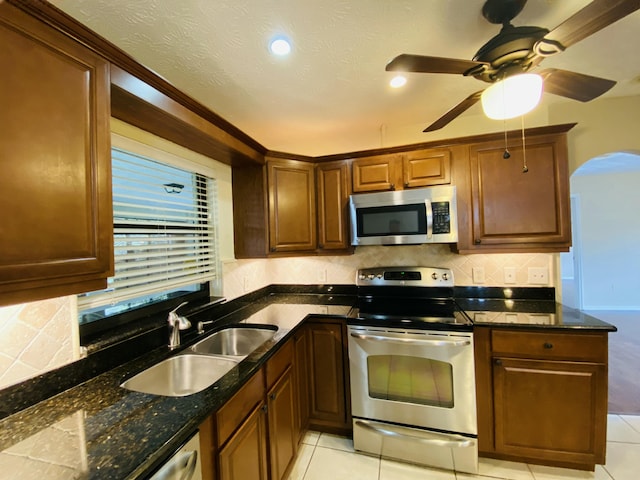 kitchen featuring light tile patterned floors, sink, appliances with stainless steel finishes, and dark stone counters