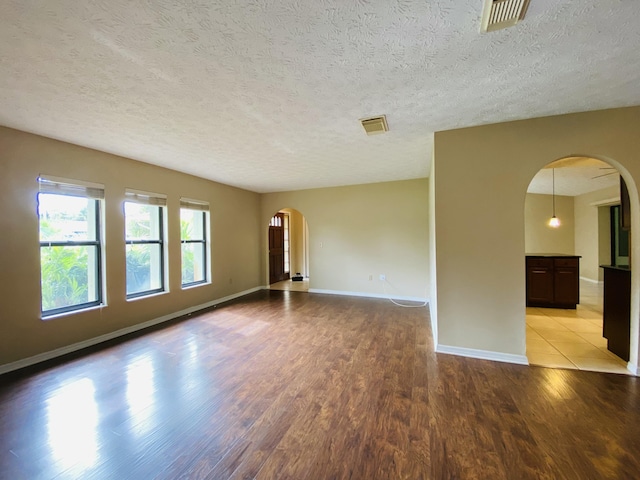 unfurnished room with light wood-type flooring and a textured ceiling