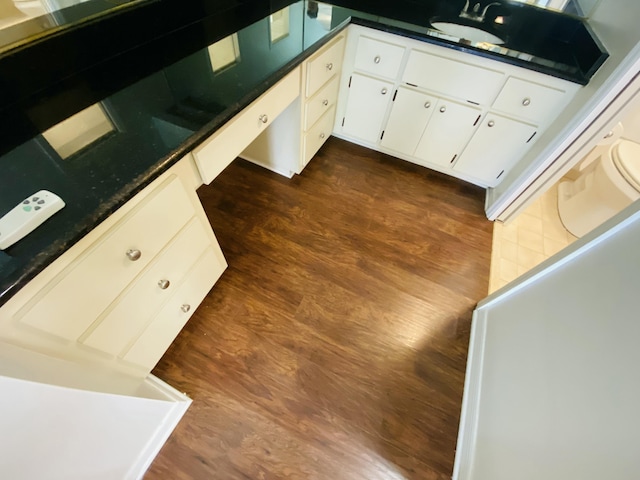 kitchen featuring dark hardwood / wood-style floors, white cabinetry, sink, and dark stone counters