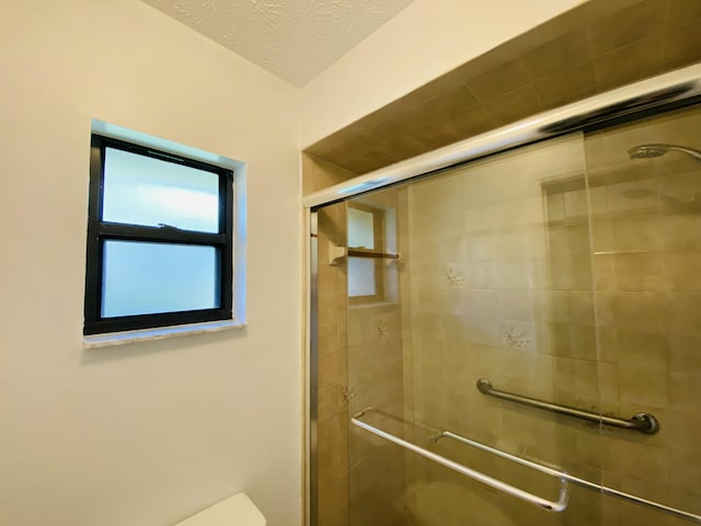 bathroom featuring a textured ceiling, toilet, and walk in shower